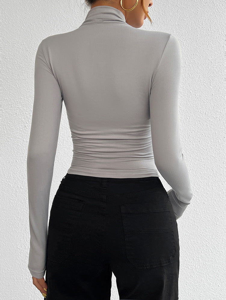 Person wearing a gray long-sleeve top and black pants against a white background