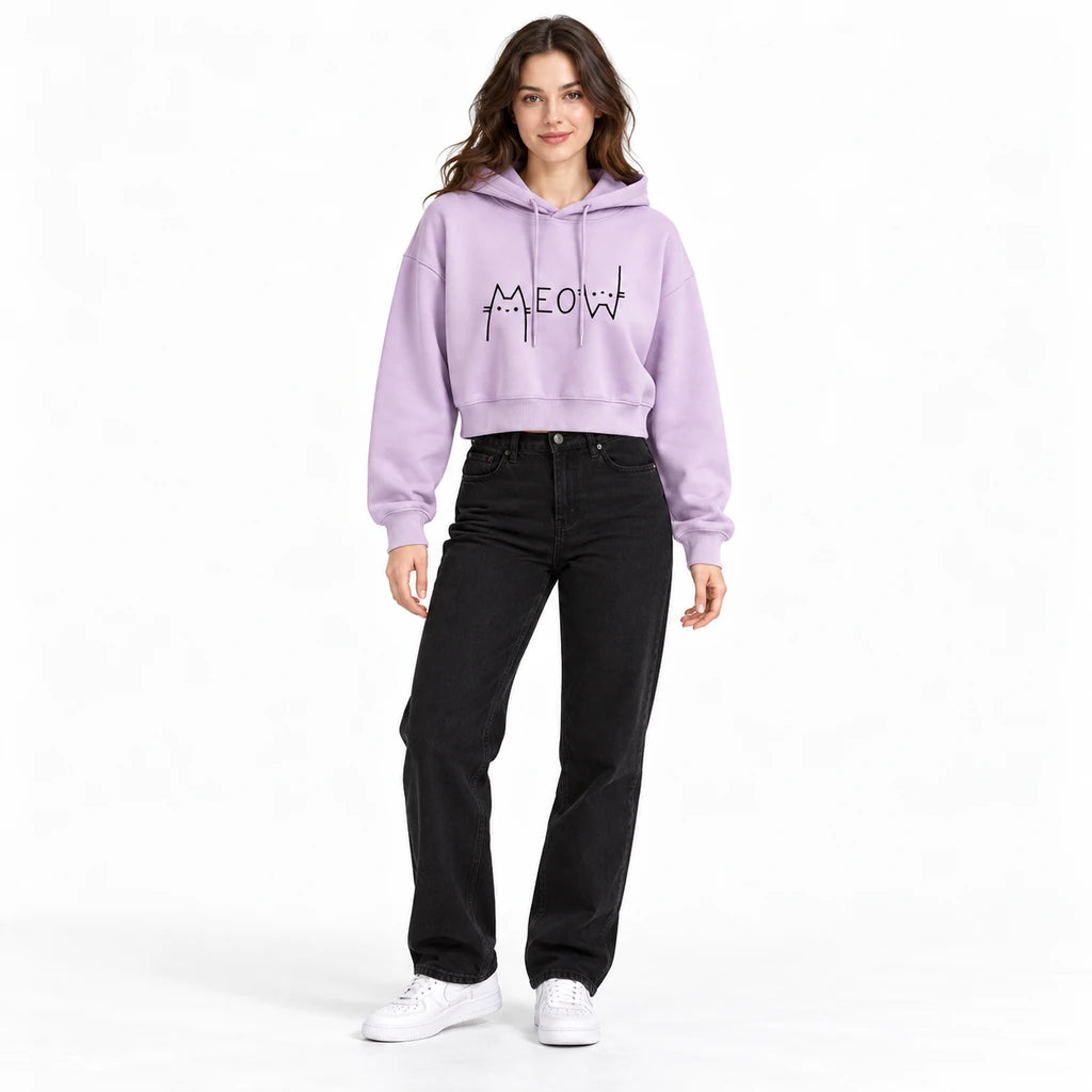 Lilac Meow cropped hoodie on a full-body model with black denim, showing the black cat graphic, long sleeves, and ribbed hem.