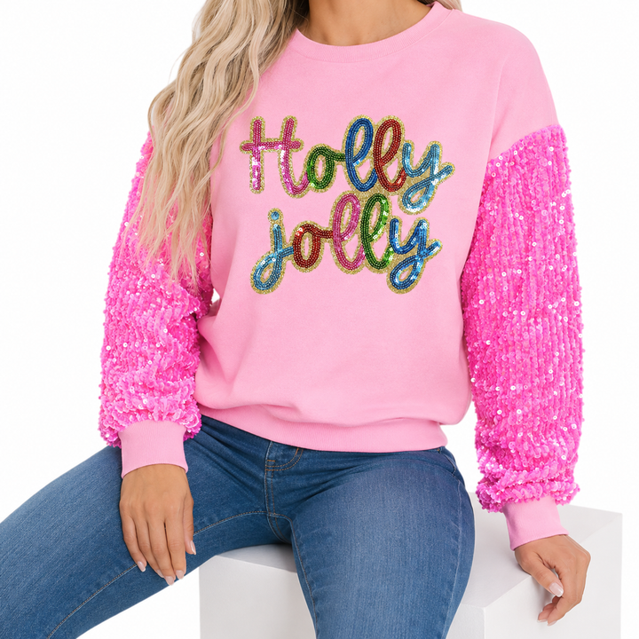 Seated styling view of pink Holly Jolly sequin sweatshirt and jeans