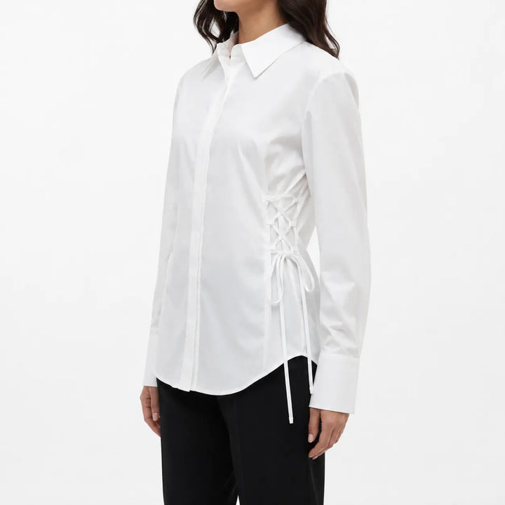 Three-quarter side fit view of the white blouse on a female fashion model, highlighting the lace-up waist and cuffed sleeves.