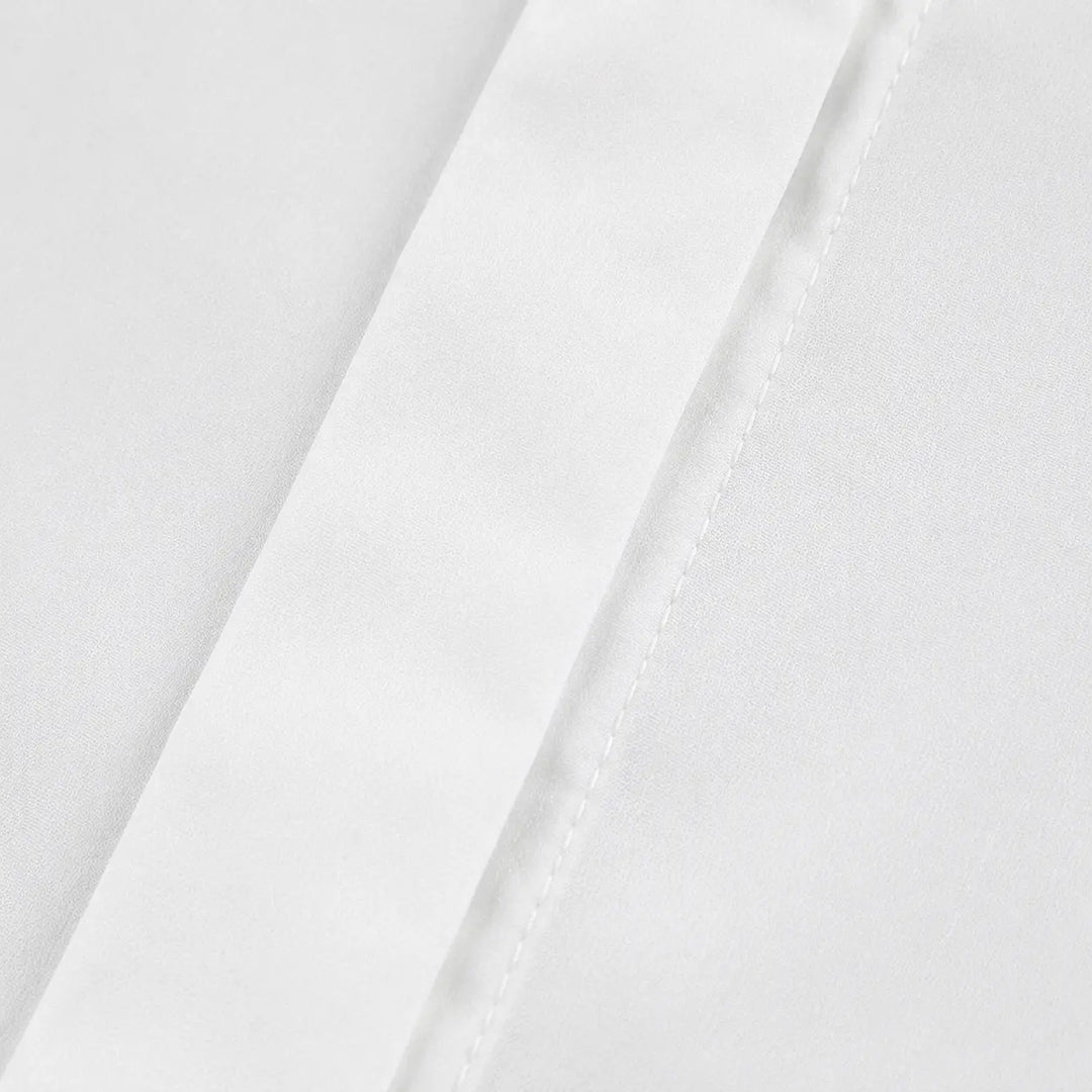 Macro view of the white blouse fabric and seam finish, with its clear surface texture, concealed placket, and neat stitching.