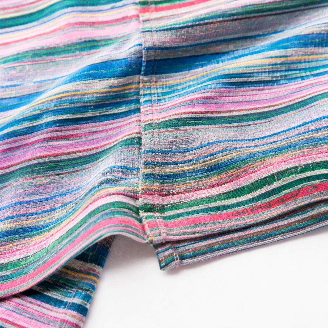 Macro view of multicolor striped pant fabric and seam construction, photographed up close on a clean white studio background.