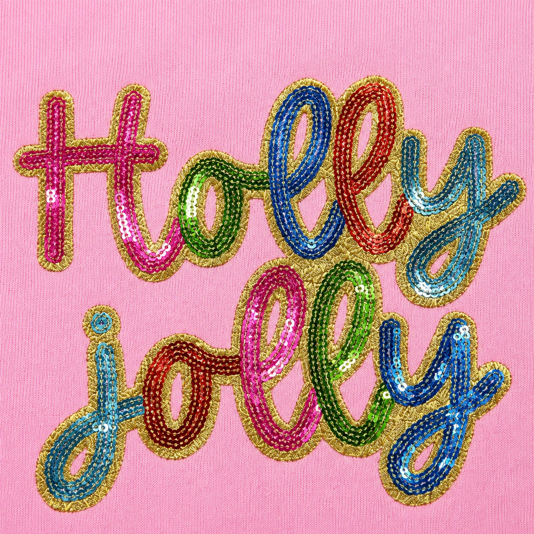 Close-up of multicolor Holly Jolly sequin lettering on pink knit