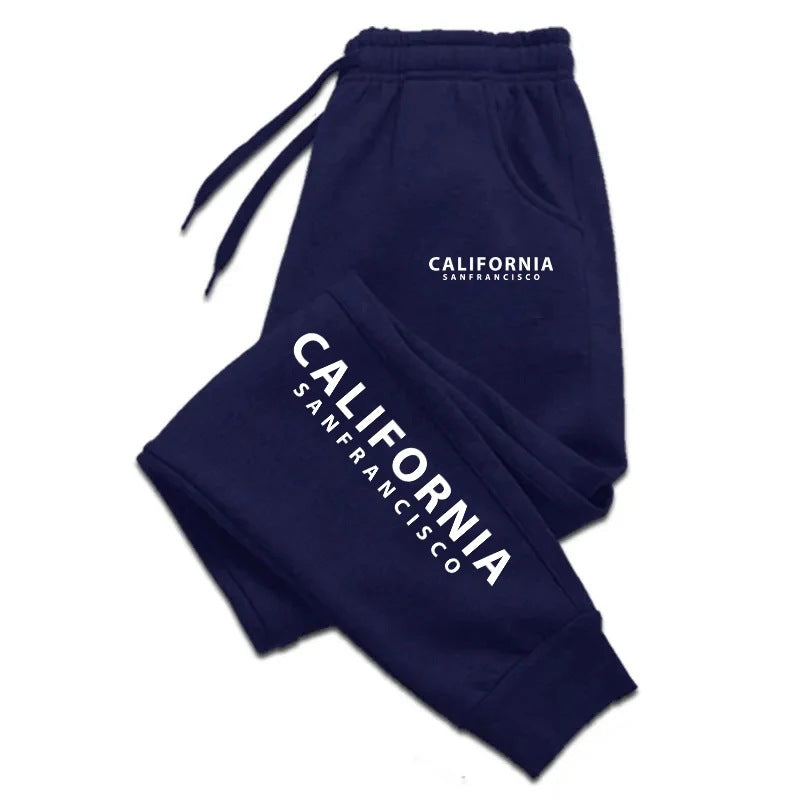 Navy blue California print sweatpants with white lettering, a gathered waistband and cuffs, folded on a plain white backdrop.