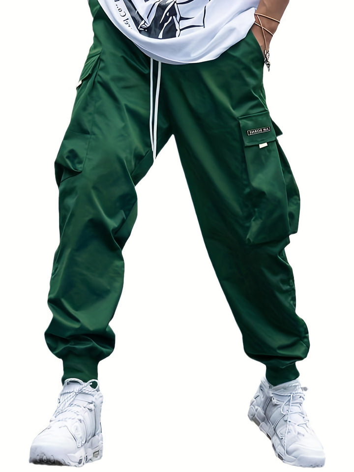 Green cargo pants worn with a white shirt and white sneakers on a white background