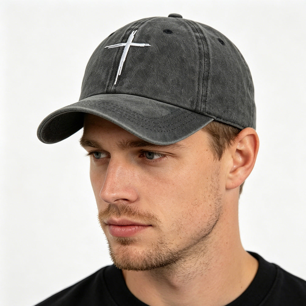 Man wearing a gray cap with a white cross on a plain background