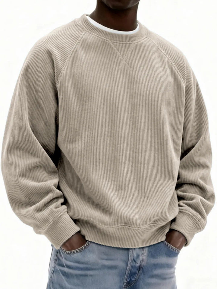 Person wearing a beige corduroy sweatshirt and blue jeans on a white background