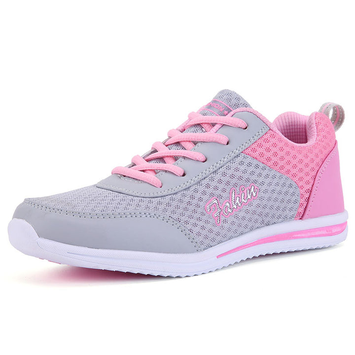 Gray and pink mesh sneakers shown from a front three-quarter angle, with pink laces, gray overlays and a low flat white sole.