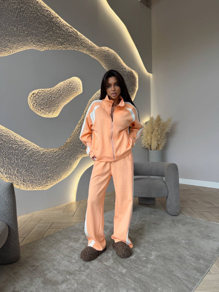 Person wearing a peach tracksuit in a modern room with abstract wall art.