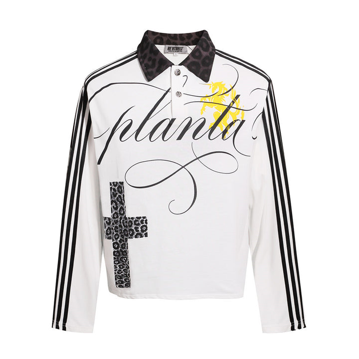 White collared polo shirt seen from the front, featuring black script lettering, long striped sleeves and cross print detail.