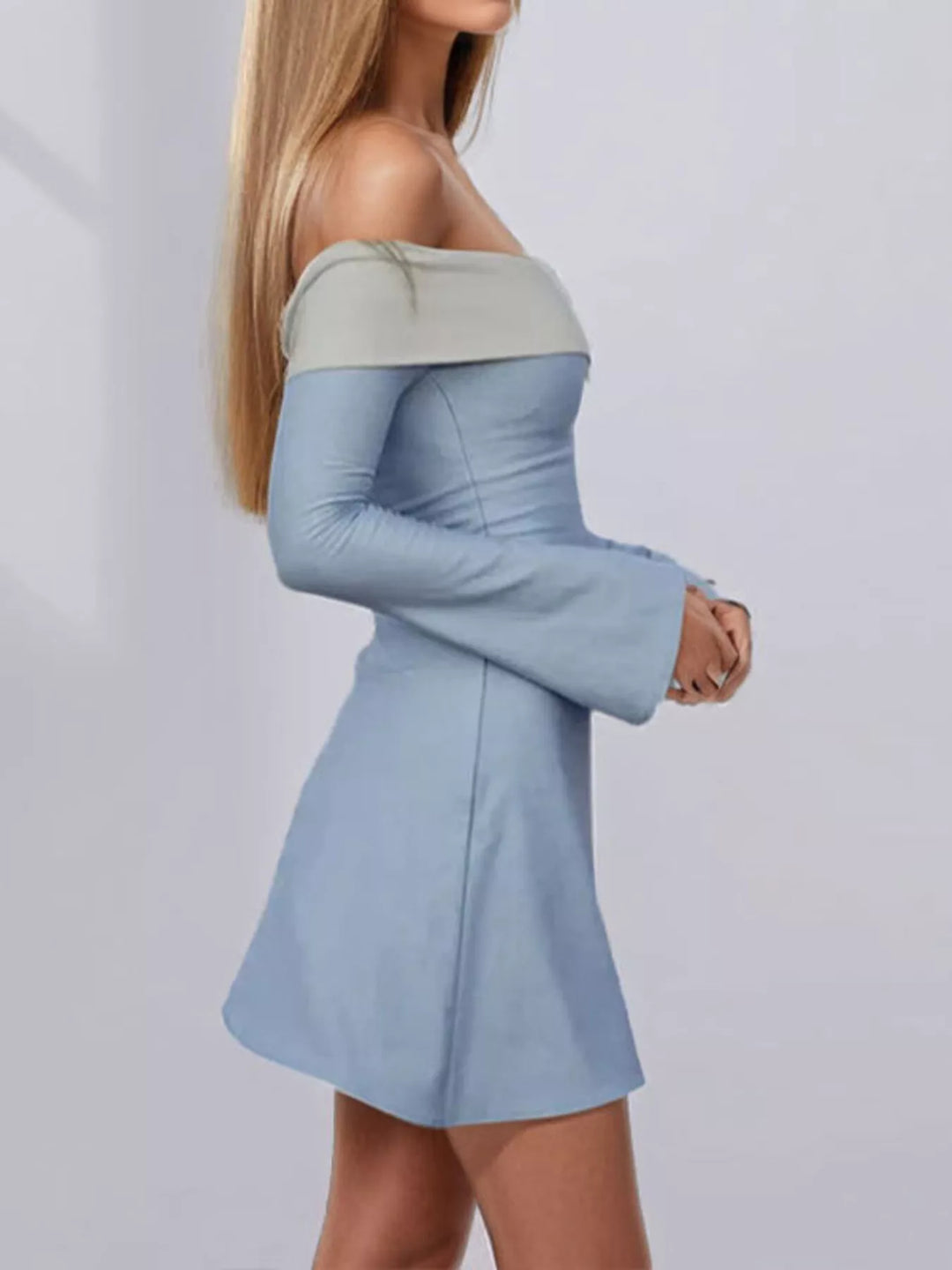 Woman wearing a two-tone dress with long sleeves and a fitted skirt on a light gray background