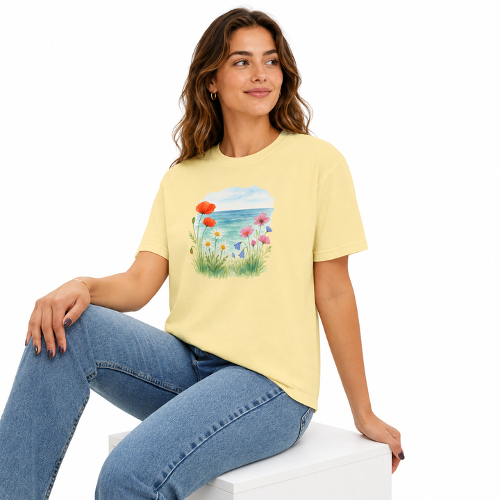Woman wearing a yellow t-shirt with a floral design sitting on a white surface.