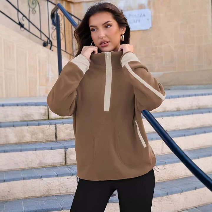 Woman wearing a brown hoodie with white accents on a staircase.