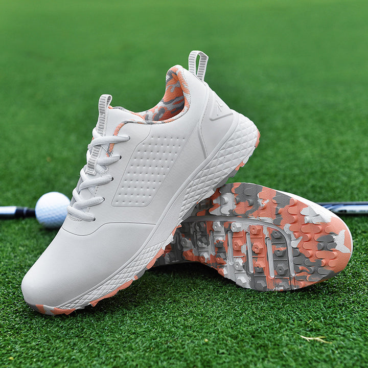 White &amp; pink rotary buckle shoes on golf-course grass, with one shoe upright and the other showing the patterned studded sole
