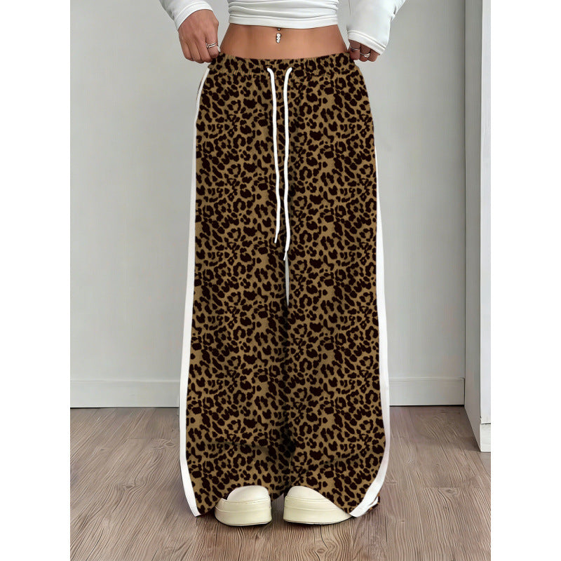 Leopard print pants with a white drawstring worn by a person on a wooden floor.