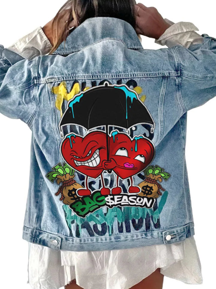 A light blue denim jacket with a large colorful cartoon graphic on the back, shown on a model from behind. The graphic features two red hearts under a black umbrella with blue dripping paint, surrounded by green money bags and the words &