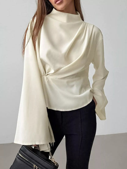 Asymmetrical ruched top mock neck blouse flat lay showing zipper and long sleeves with tailored trousers styling
