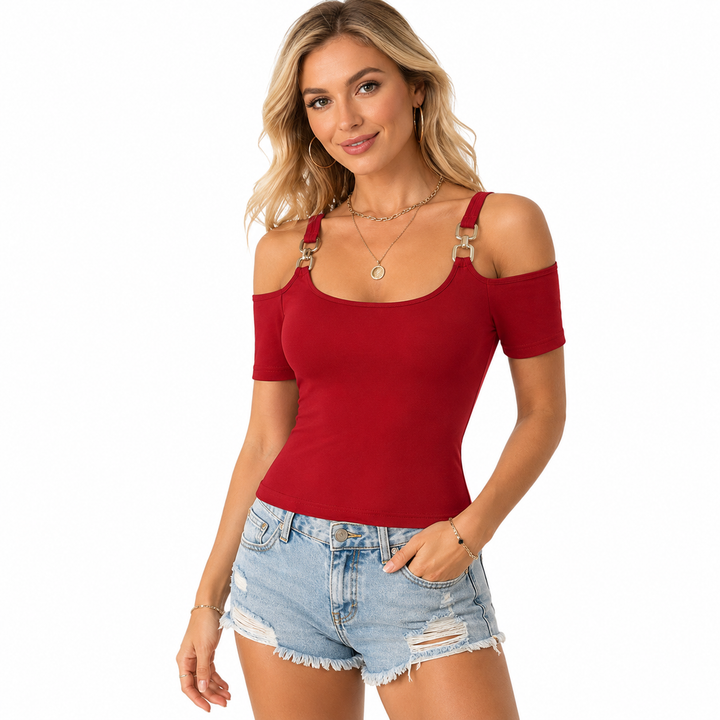 A woman modeling a red cold-shoulder short-sleeve top with decorative gold-toned strap details, paired with light-wash distressed denim shorts, against a plain white background.