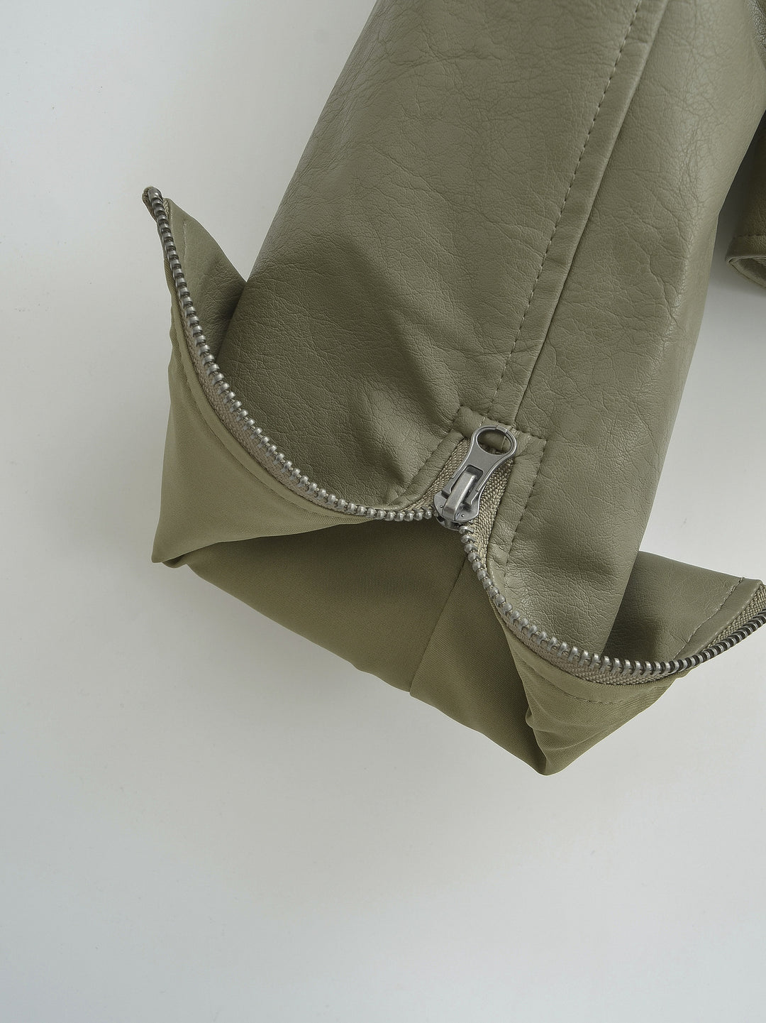Gray Green sleeve cuff close-up, showing an opened zipper, with visible stitching and the folded sleeve edge in close detail.