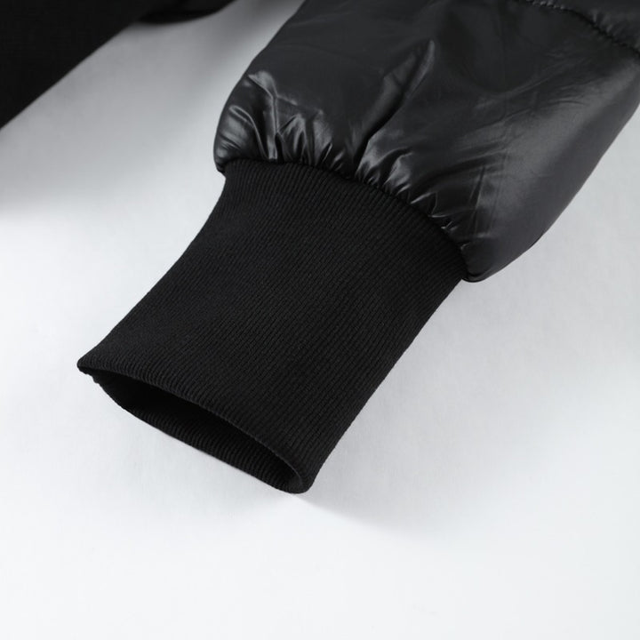 Close-up of a black quilted jacket sleeve on a white background