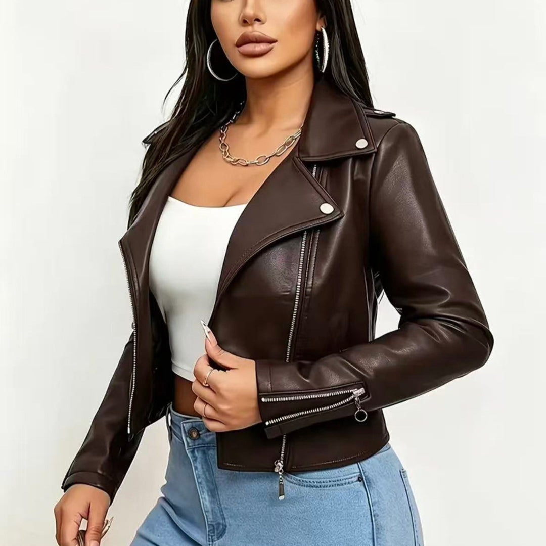 Chocolate Brown cropped moto jacket on a model, with silver lapel snaps, long sleeves, the front zipper and zip cuff details.