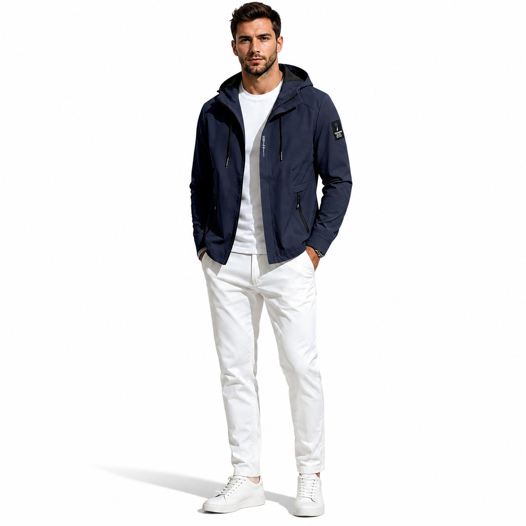 A man modeling a navy blue hooded jacket over a white t-shirt and white pants, standing against a solid white background.