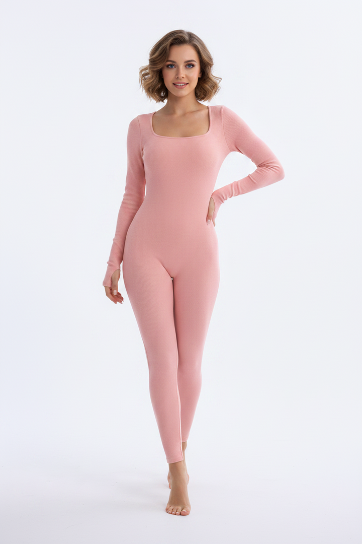 Lifestyle shot of a woman in a purple square neck jumpsuit with cropped blazer and heeled boots for night out.
