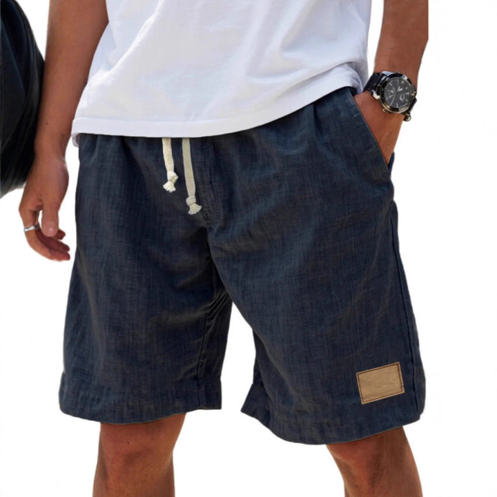 Person wearing dark denim shorts with a white shirt on a white background