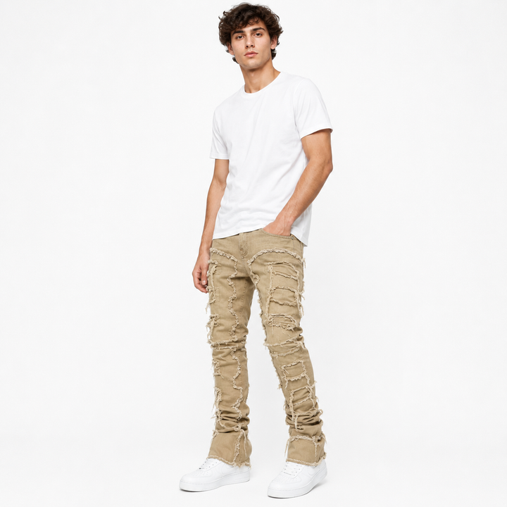 Stacked jeans for men featuring distressed texture, fringe trim, and structured fit