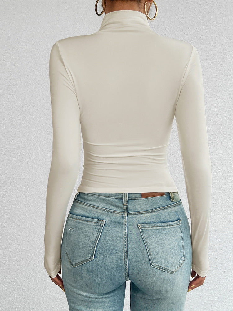 Person wearing a beige long-sleeve top and light blue jeans against a white background