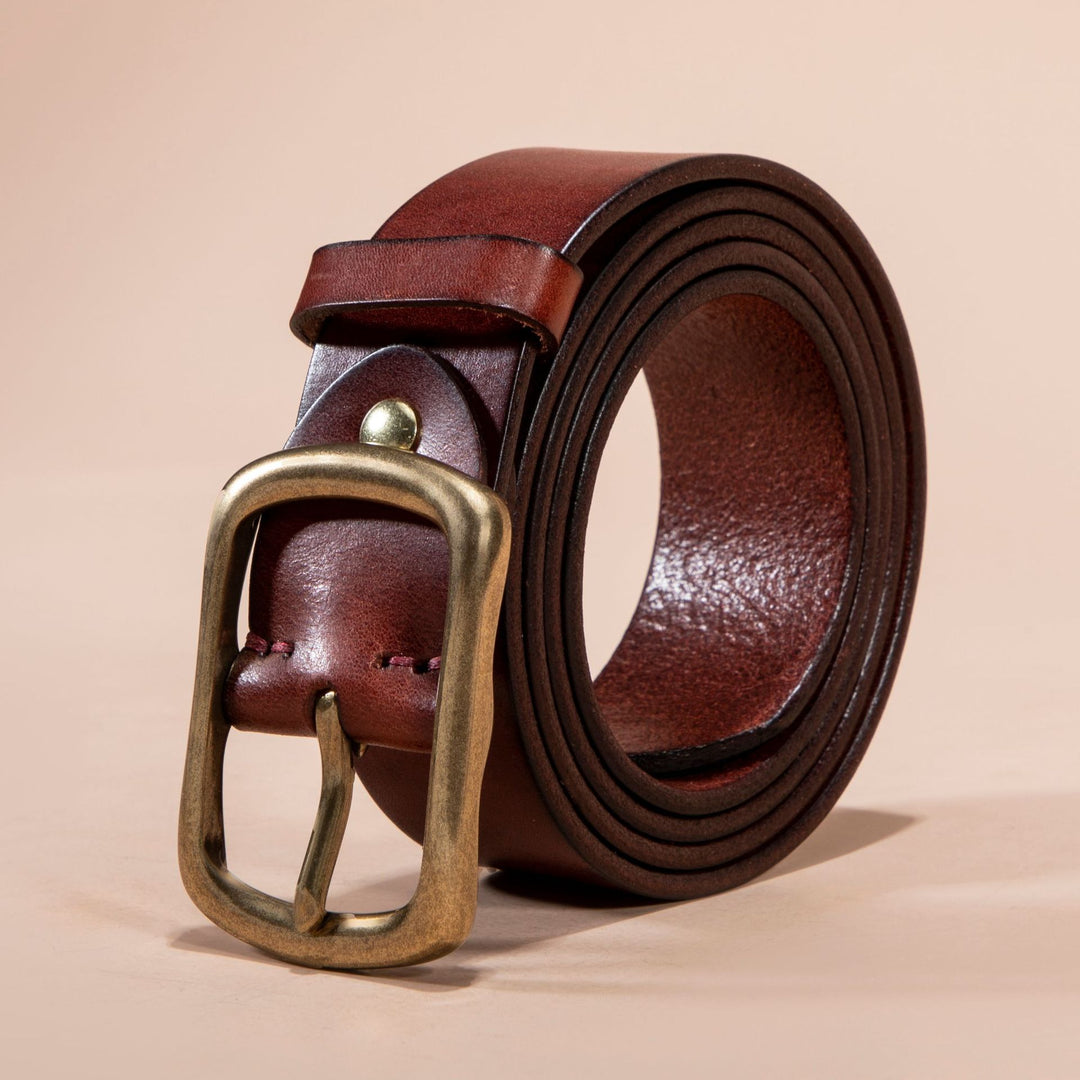 Brown leather belt with a gold buckle on a beige background
