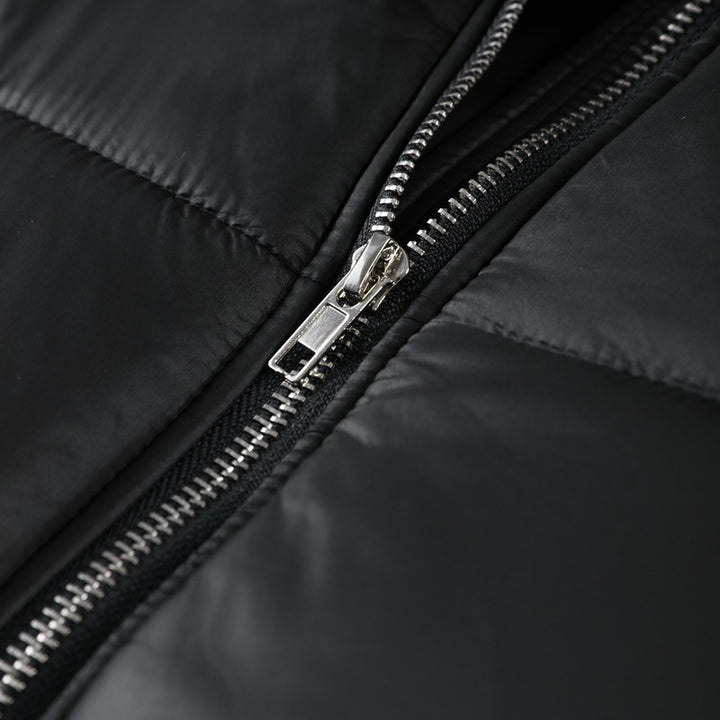 Close-up of a black jacket zipper with a silver zipper pull on a black background