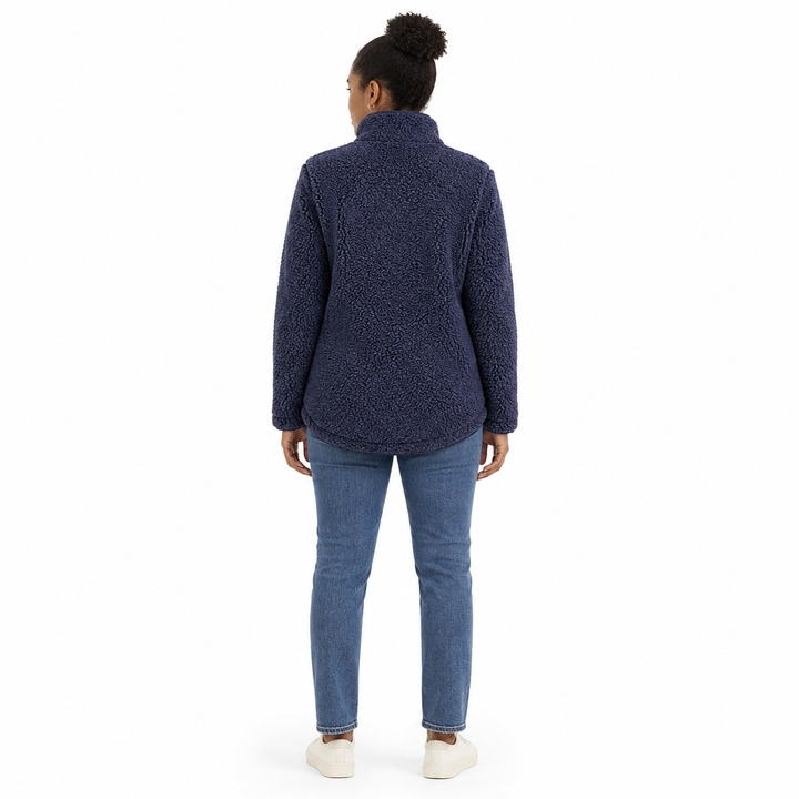A woman viewed from the back wearing a textured navy blue fleece jacket, blue jeans, and white slip-on shoes against a plain white background.