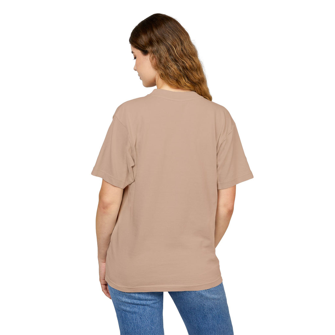 Person wearing a beige t-shirt with a graphic design on the back, standing against a white background
