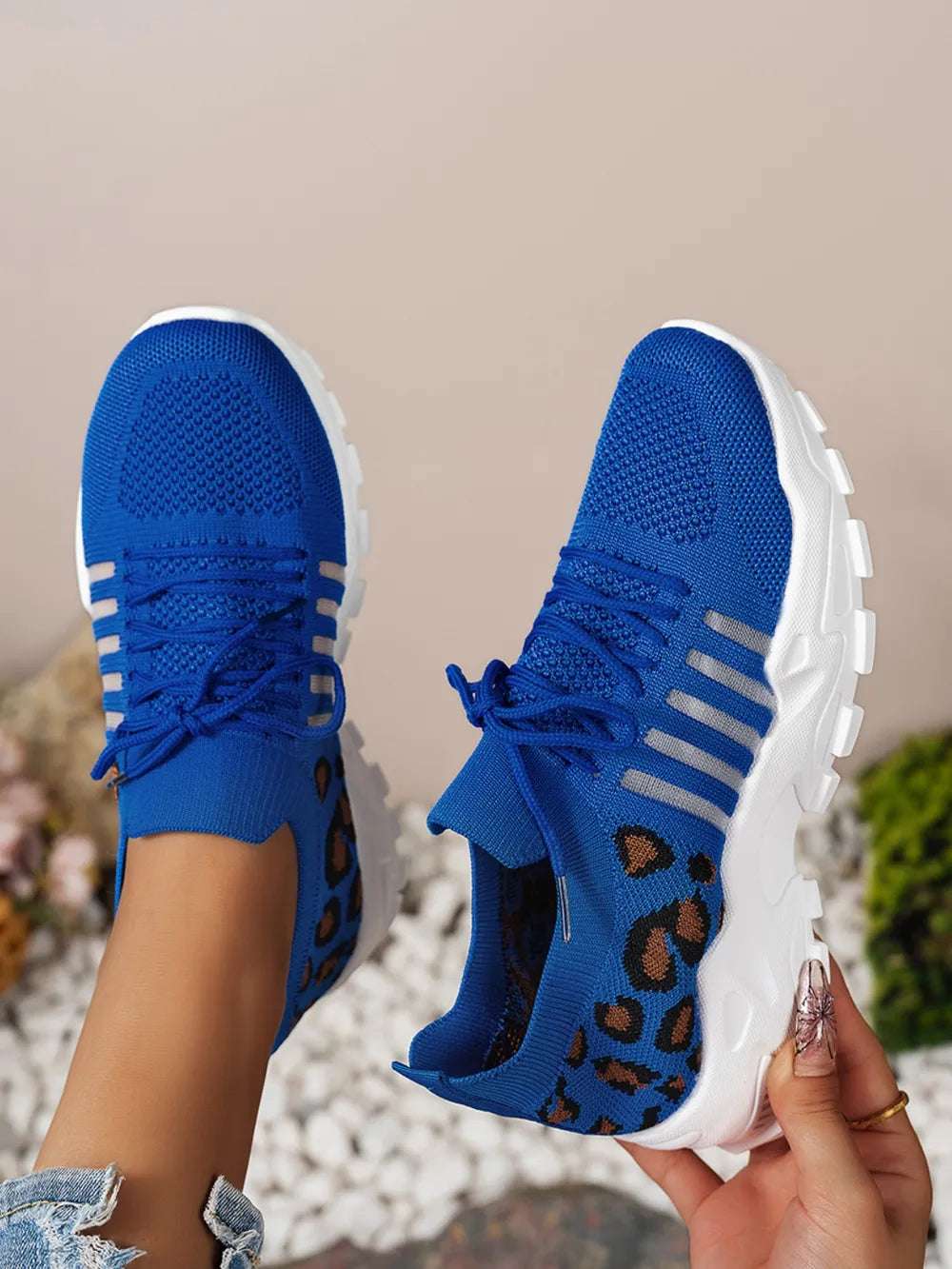 Woman tying laces on leopard mesh sneakers before a workout

