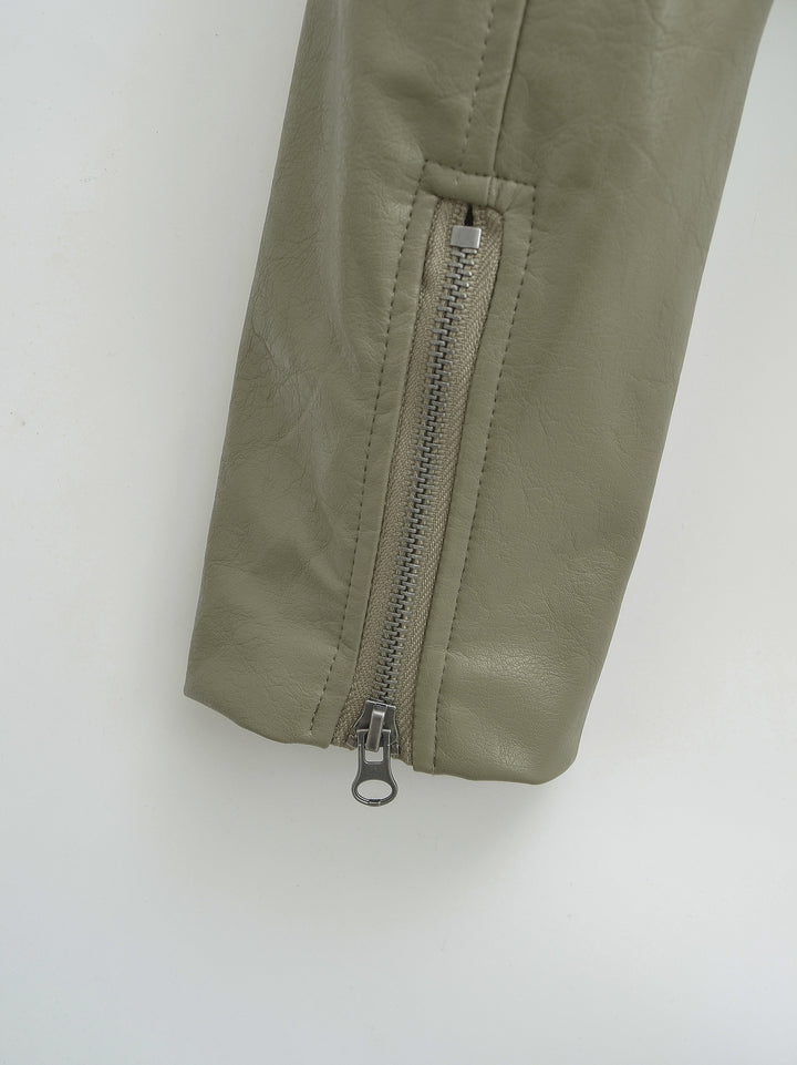 Gray Green jacket sleeve close-up showing the closed cuff zip with its silver pull and straight seam stitching against white.