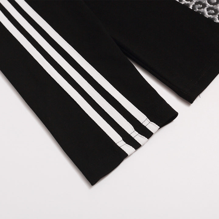 Black polo shirt sleeve detail showing three white stripes, straight sleeve opening and a section of the cross-pattern print.