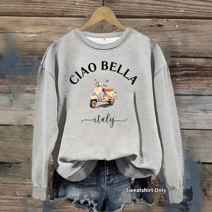 Heather gray Ciao Bella scooter print sweatshirt with long sleeves, ribbed neck and cuffs, hanging above denim shorts on wood