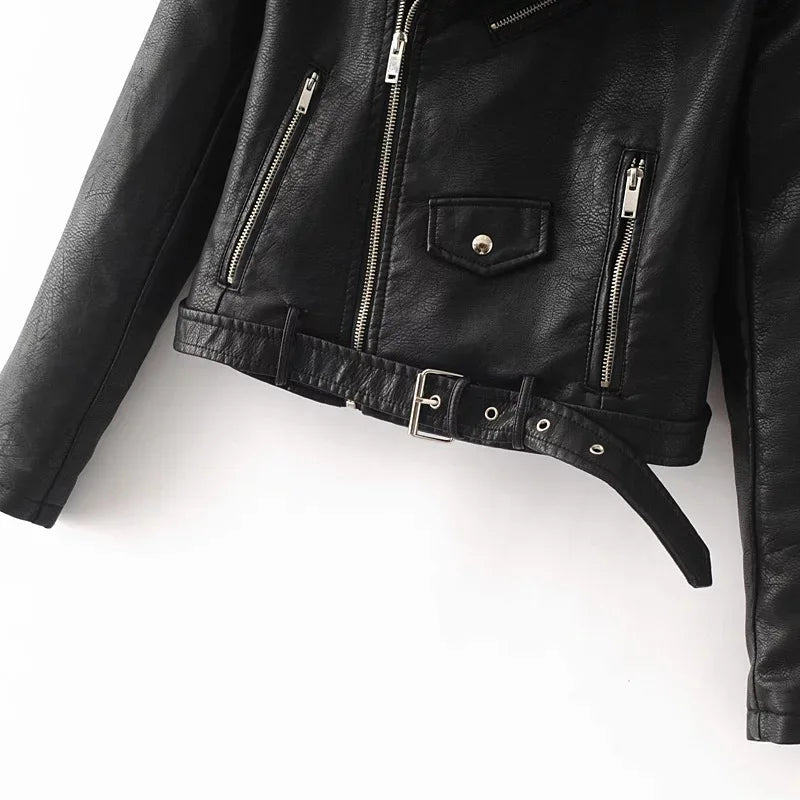 Black jacket lower front close-up showing the vertical zipper details, snap-flap pocket and matching hem belt and its buckle.