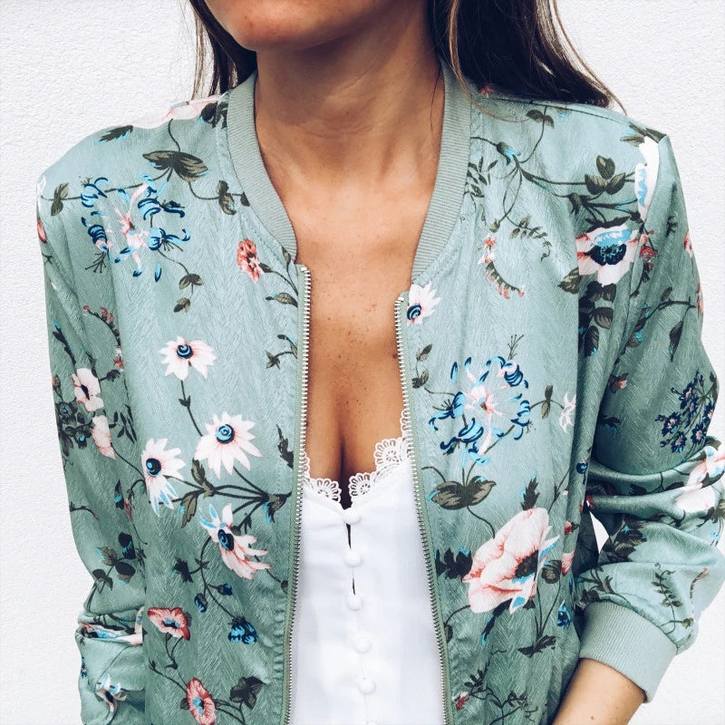 Close front view of the Green printed jacket worn open over a white top, showing this floral design, collar and front zipper.