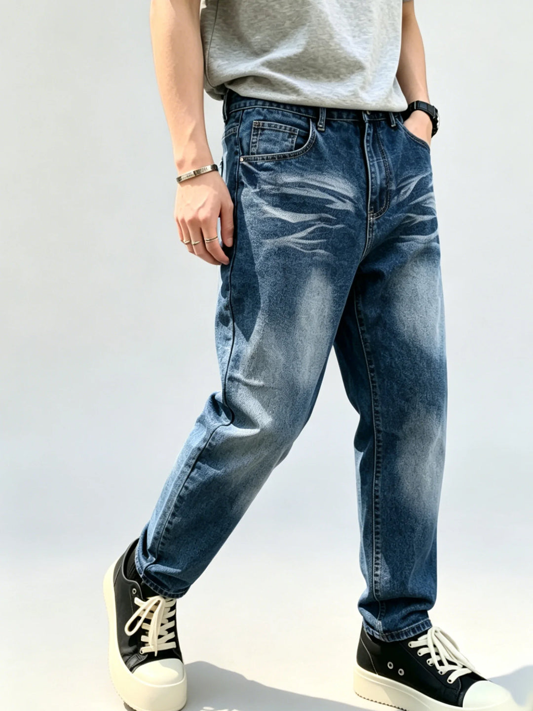 Angled front view of blue jeans highlighting the mid-rise waistband, front coin pocket, faded thighs and loose straight legs.