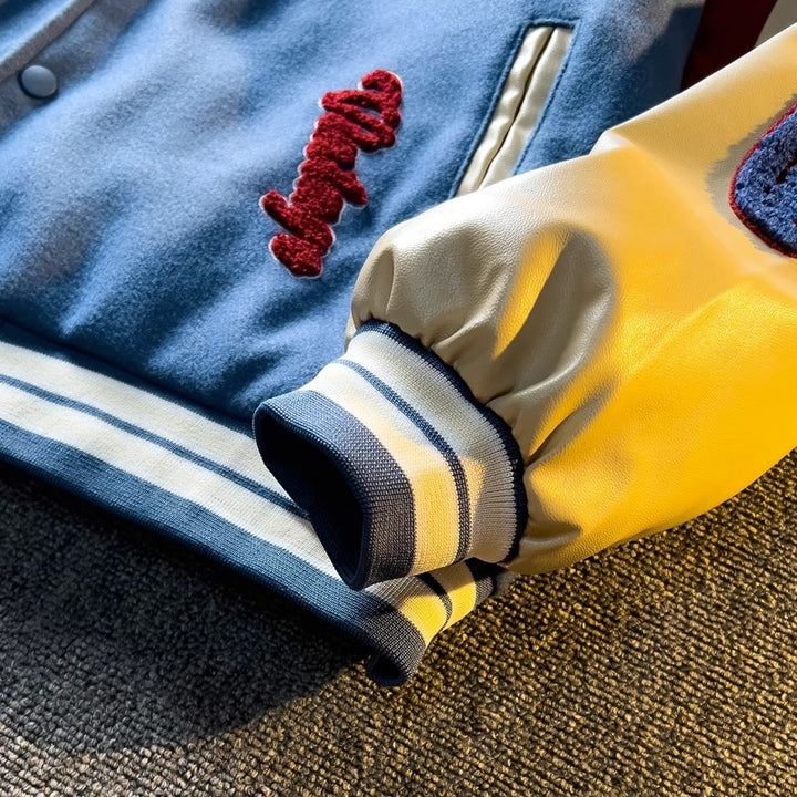 WT167 jacket in Blue shown in a close detail view showing the cream sleeve and striped ribbed cuff, on a gray fabric surface.