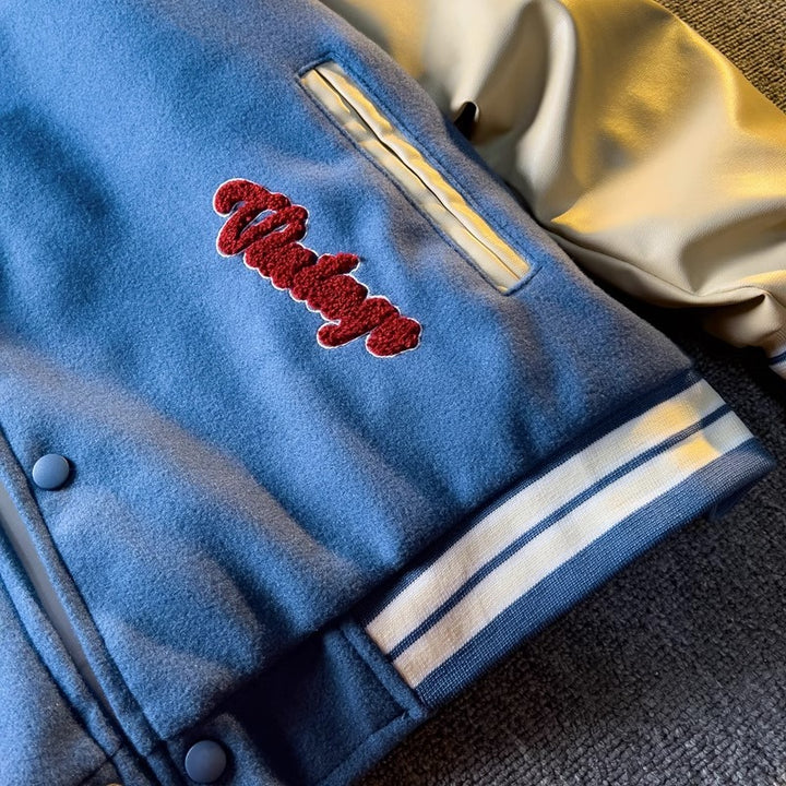 WT167 jacket in Blue shown in a close detail view, with the red embroidered front detail visible, on a gray textured surface.