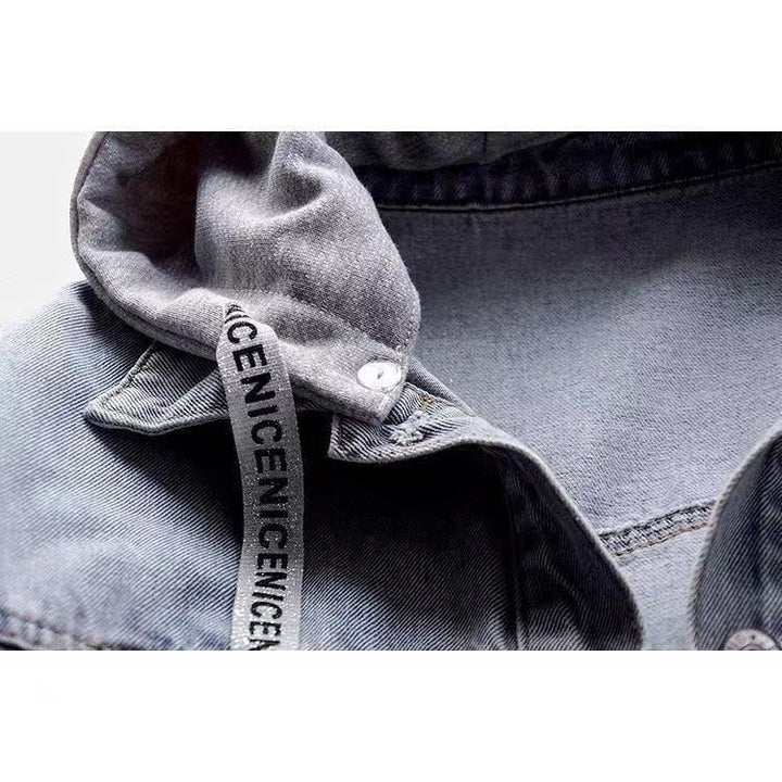 Grey hood attachment and printed drawstring on the blue denim jacket, with metal snap, collar seam and woven fabric close up.