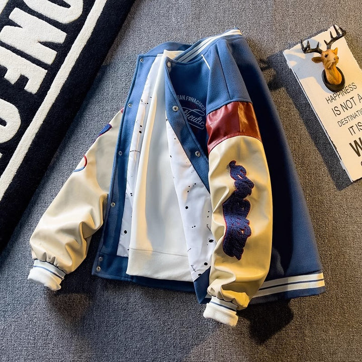 WT167 jacket in Blue shown in a front product view, showing contrast sleeves and embroidery, against a gray textile backdrop.