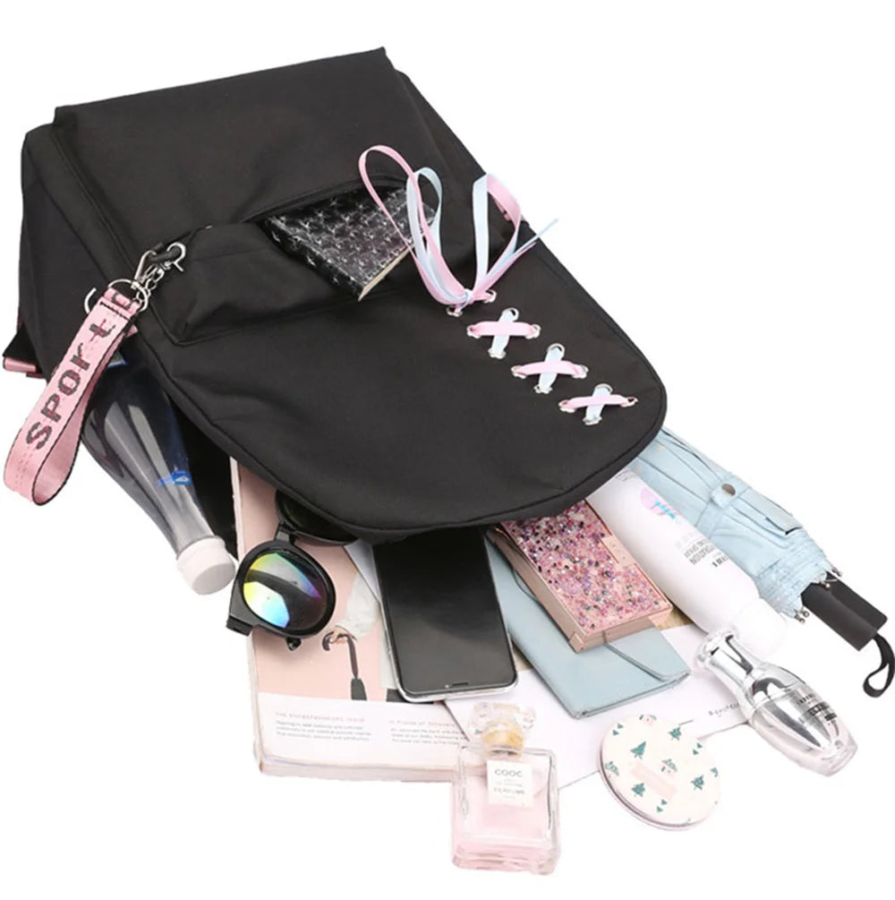 Plain black reference school backpack opened beside books, a phone and other props to illustrate a packing example in detail.