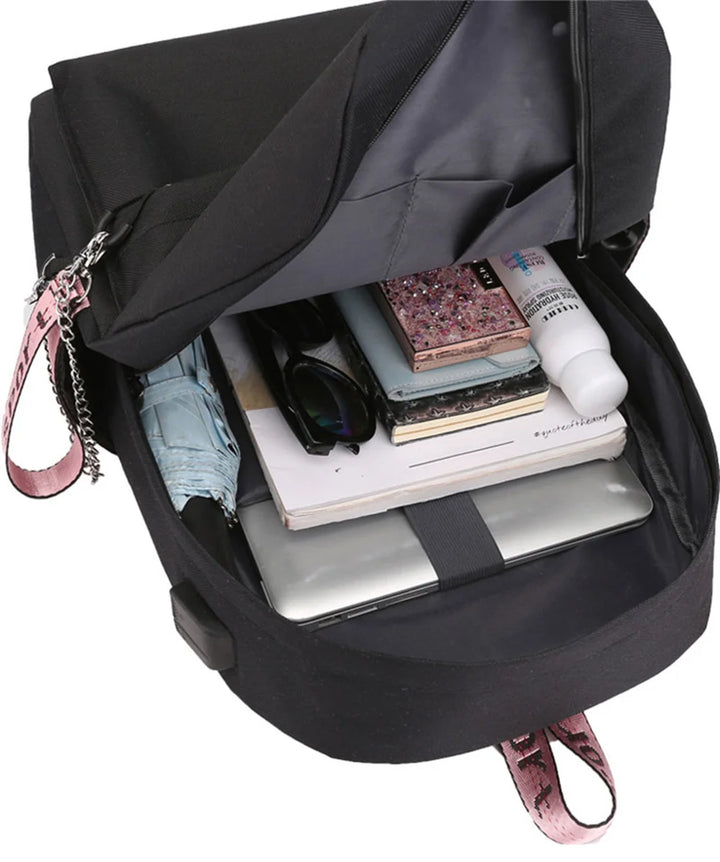 Open black reference backpack holding books, a laptop and small items as a packing example featuring nylon lining in a photo.