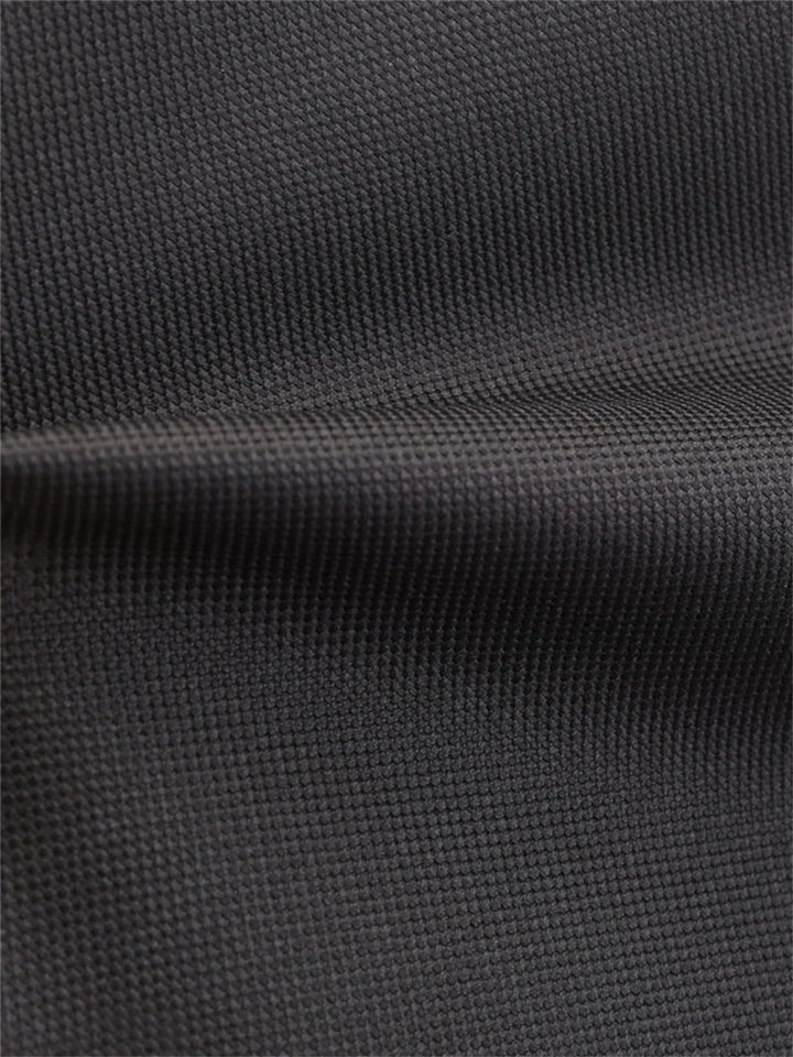 Close-up of black woven school backpack fabric, showing its visible surface grain and a softly folded seam area in the photo.