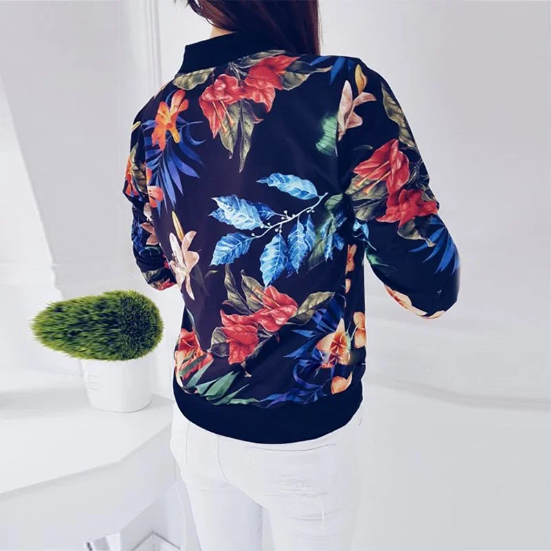 Dark Blue printed bomber jacket shown from the back, showing big red flowers, green leaves, blue foliage and dark ribbed hem.