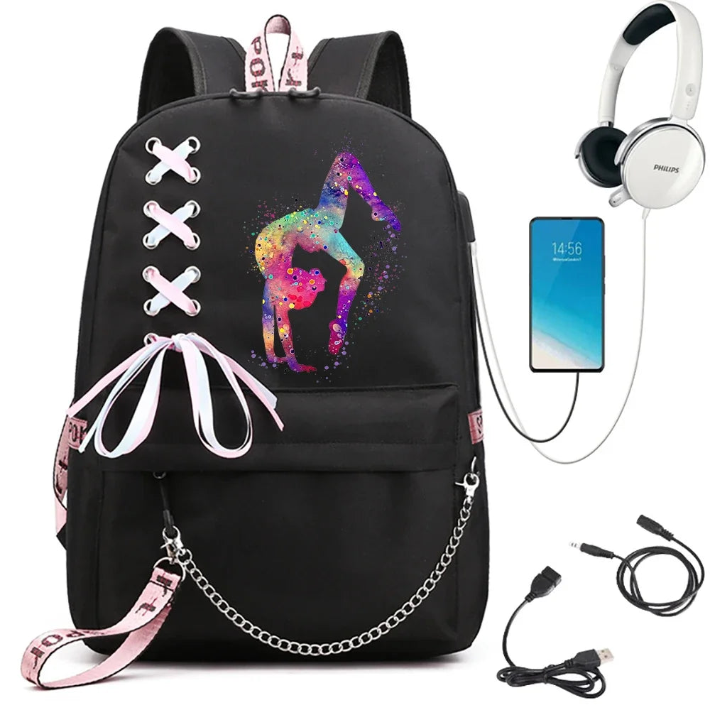Black backpack featuring colorful arched gymnast artwork, ribbon crosses and a pink bow, beside electronics props in a photo.